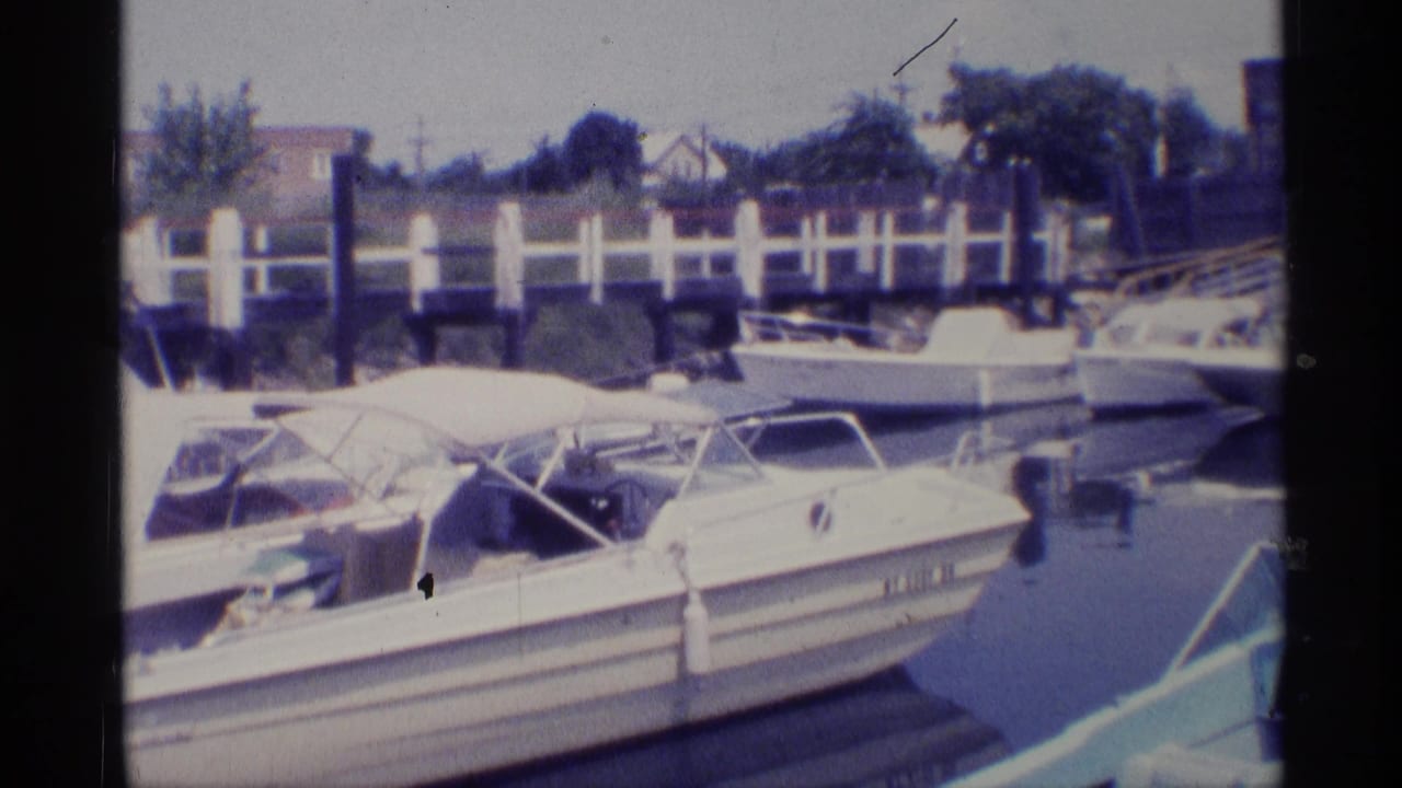 Docked white motorboats with canopy frames beside a marina railing.