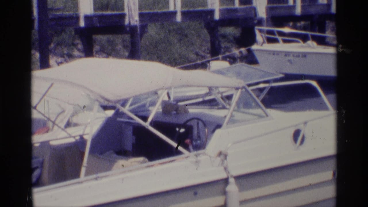 White motorboat with canvas canopy docked beside a pier.