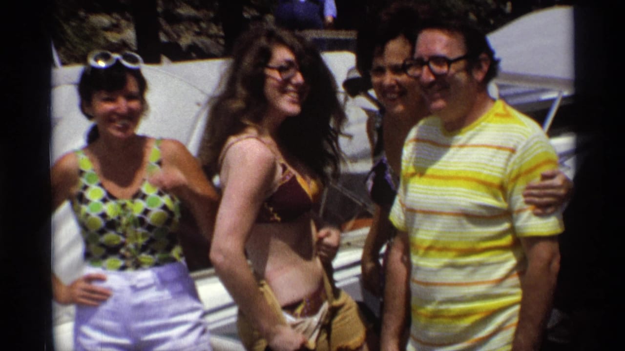 Close 8mm frame of young adults smiling together on a docked motorboat in the supplied 1973 New York footage.