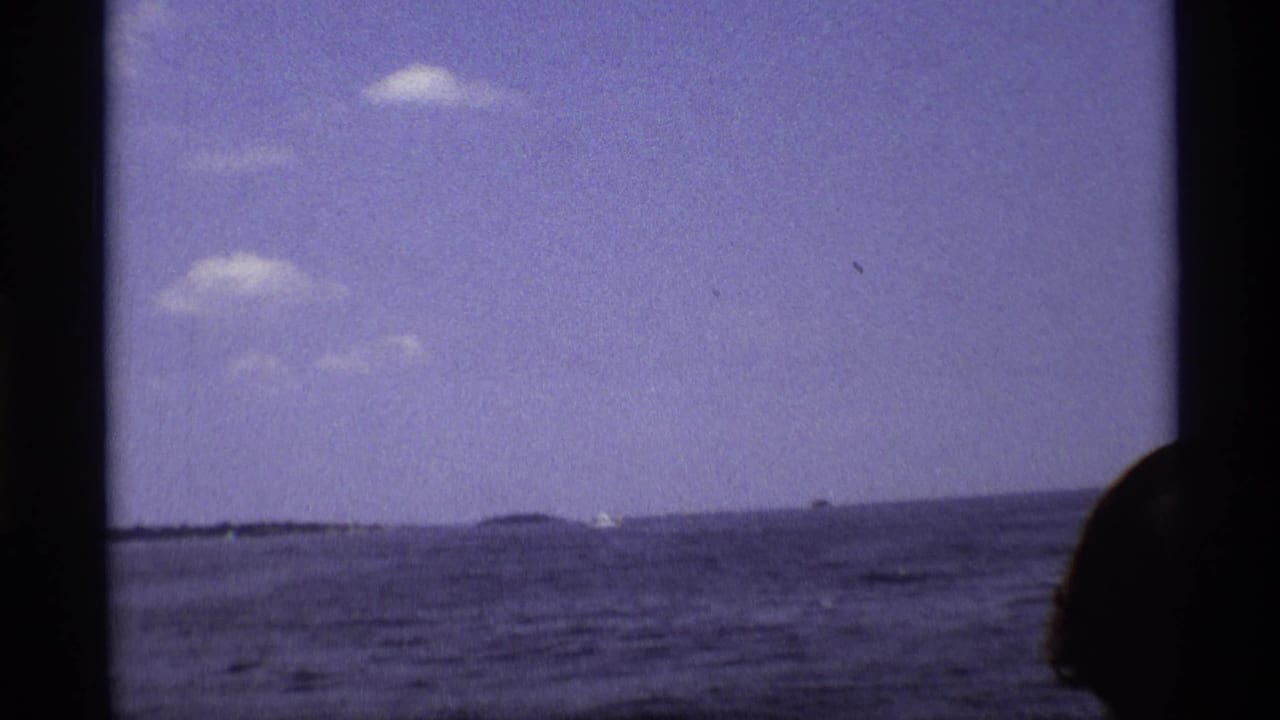 Open water and horizon seen from a boat, with part of a passenger at the right edge.
