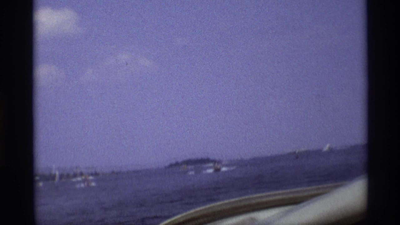 Motorboats on open water with distant low islands and dark film-frame borders.