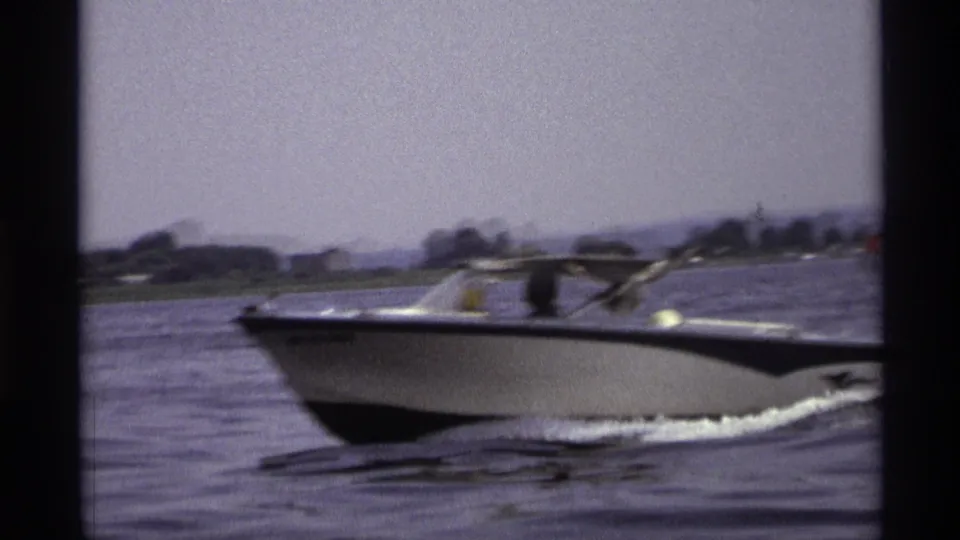 The motorboat appears nearer the camera in this 1973 New York lake scene, with passengers partly visible under the boat canopy.