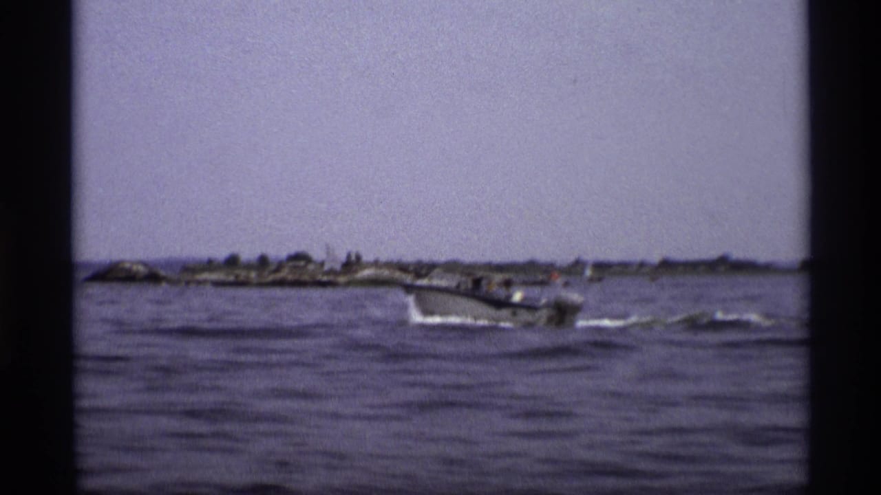 Wide 1973 New York frame with the speedboat farther from camera on open water near a low shoreline.