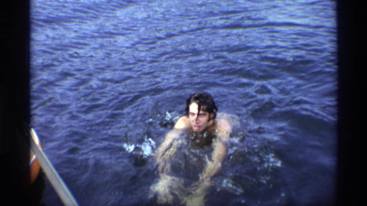 Young man swimming in dark blue water near the camera.
