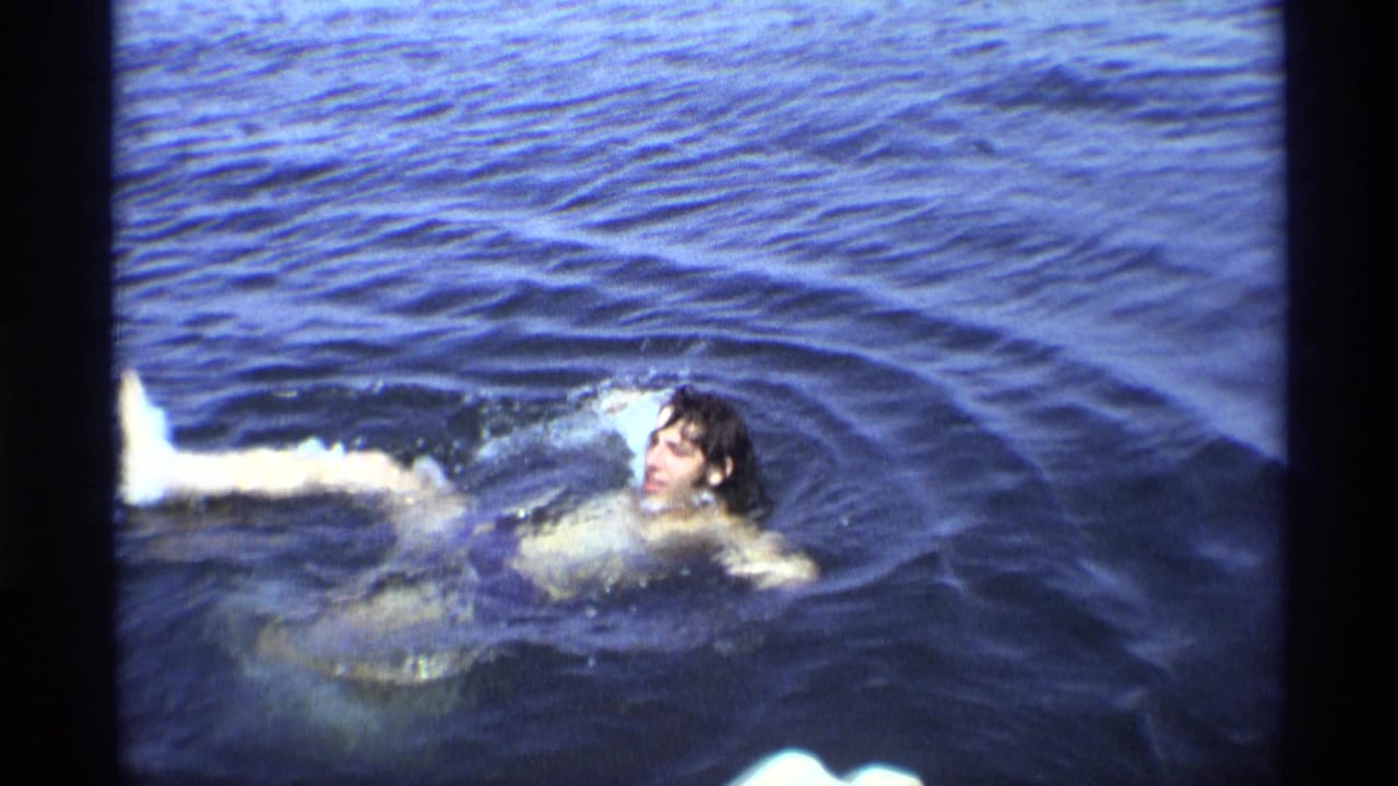 The young man appears to turn or float back in deep blue water during a short 1973 home-movie swimming shot.
