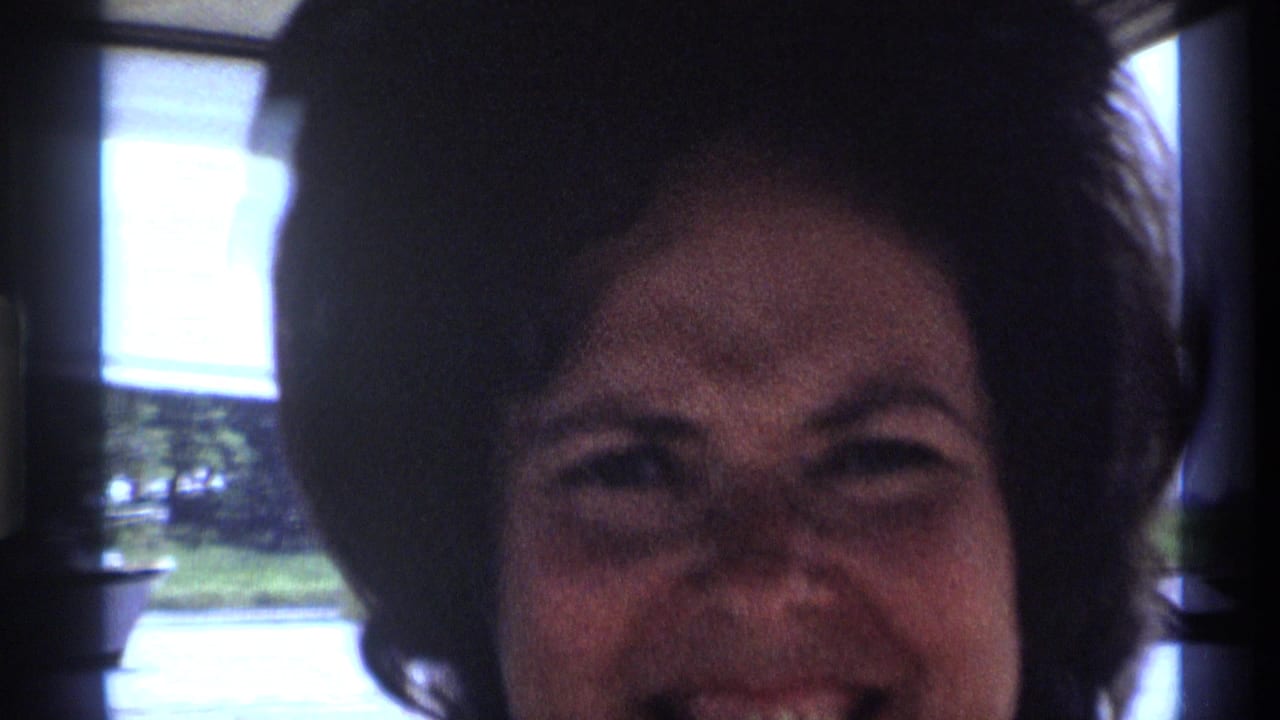 A woman with dark styled hair laughs toward the camera in 1973 New York 8mm home-movie footage.
