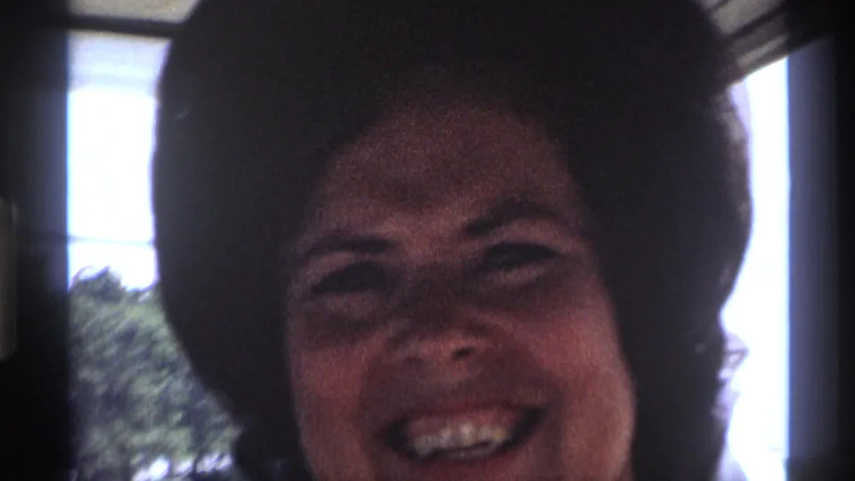 The woman smiles toward the camera near a bright window in this 1973 New York 8mm home-movie frame.