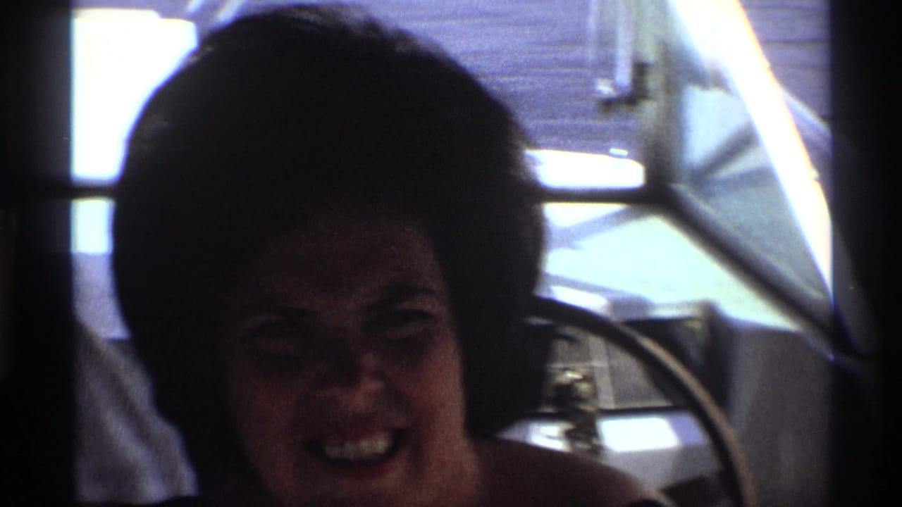 Woman laughing in shadow beside a boat windshield.