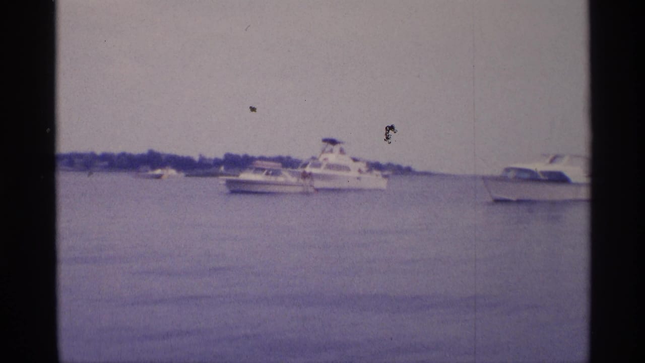 1973 New York 8mm frame showing a white cabin cruiser, smaller boats, and calm lake water.