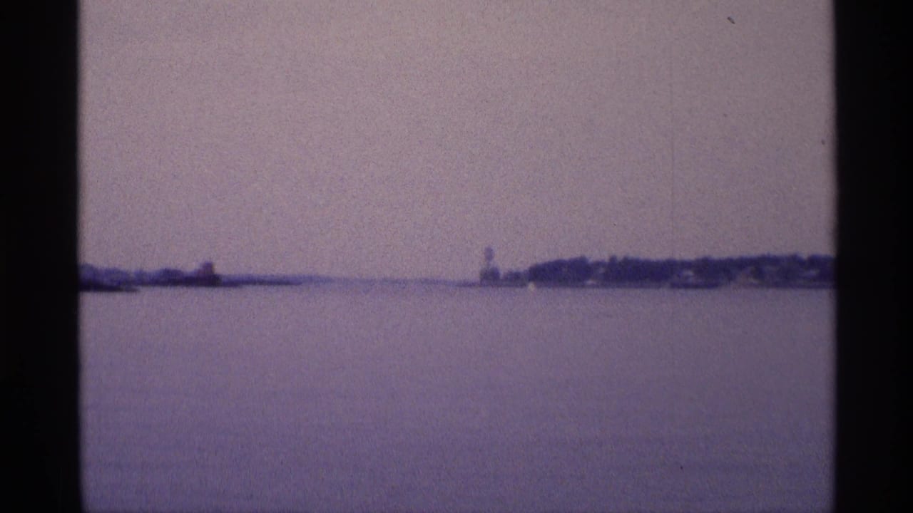 Calm water with distant shoreline and a small structure on the horizon.
