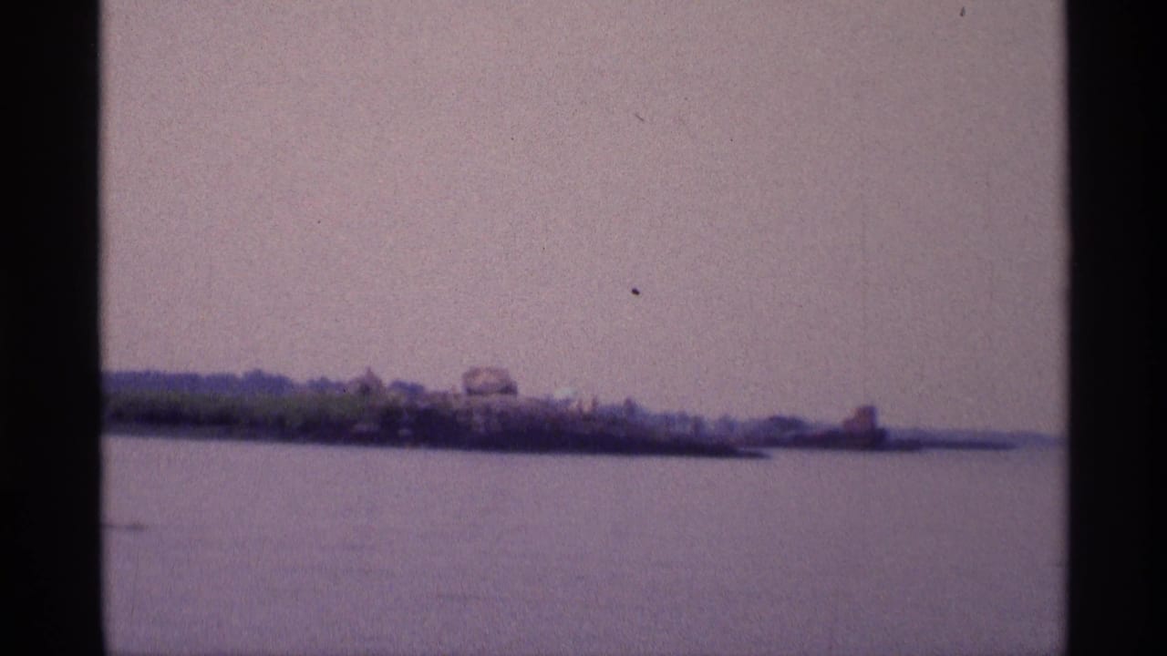 Distant shoreline across calm water under a hazy sky.