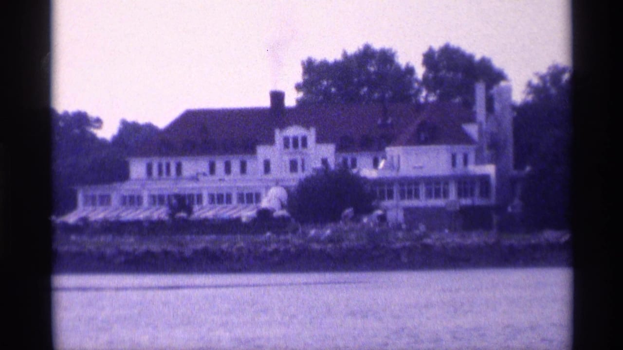 White waterfront house with striped awnings across calm water.