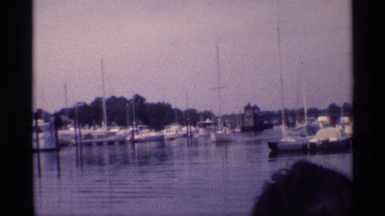A 1973 New York marina view shows moored sailboats and yachts, with a partial person visible at the lower right edge.