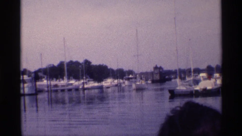A 1973 New York marina view shows moored sailboats and yachts, with a partial person visible at the lower right edge.