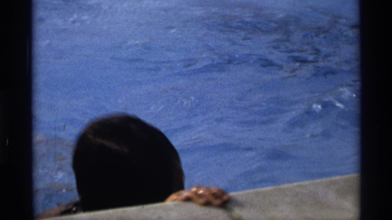 1973 New York 8mm frame of a swimmer arriving at the pool edge with head and hand visible.