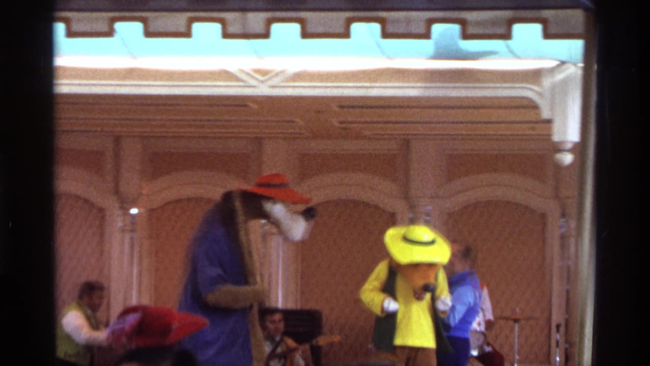 Audience-view 1974 Orlando stage scene with costumed performers interacting in front of musicians and ornate wood paneling.