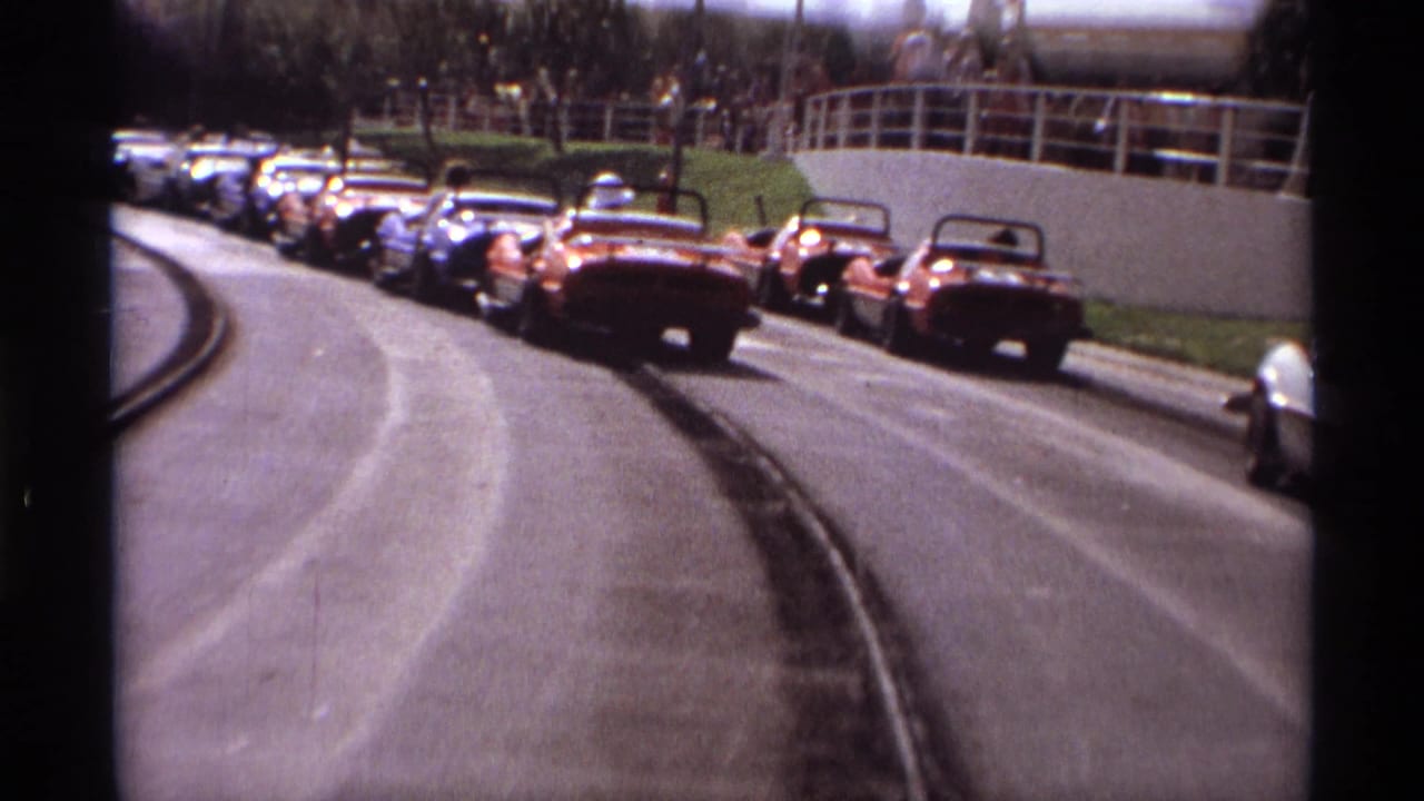 1974 Orlando 8mm footage shows bumper cars rounding a curved track with people watching from an elevated walkway.