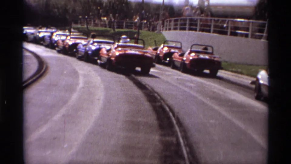 1974 Orlando 8mm footage shows bumper cars rounding a curved track with people watching from an elevated walkway.