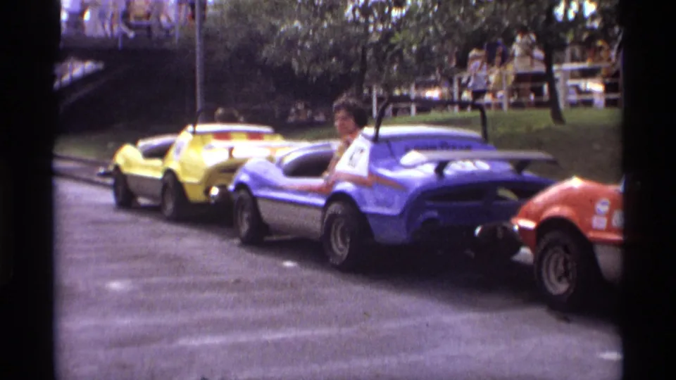 A blue bumper car with number 47 follows yellow and gray cars during the Orlando amusement ride sequence.