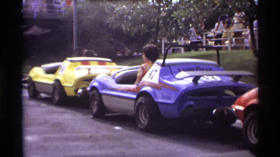 Close 1974 Orlando home-movie view of colorful bumper cars, including a blue number 47 car and nearby riders.