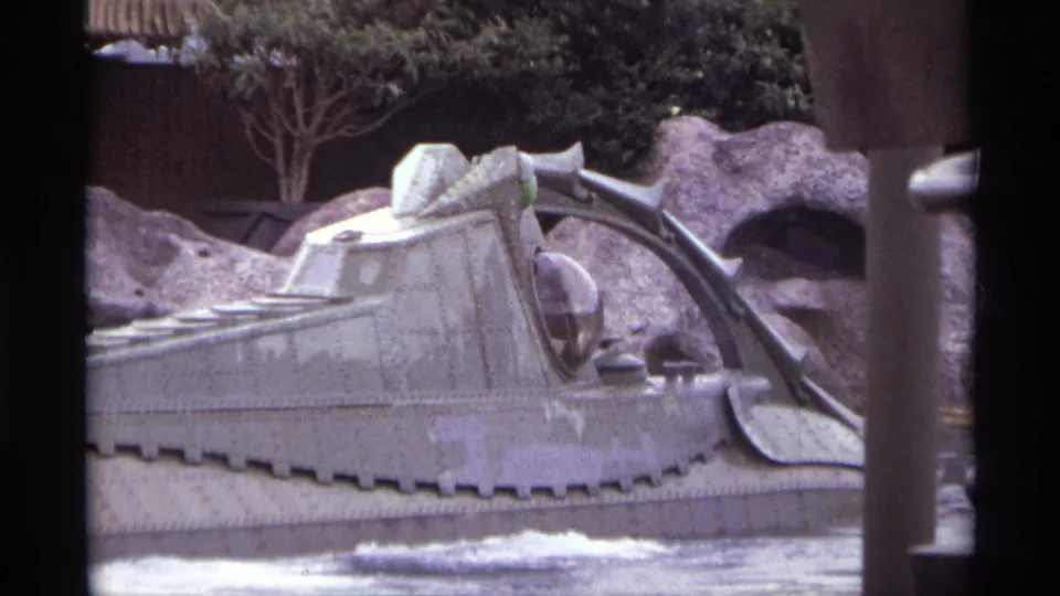 1974 Orlando 8mm frame with the gray futuristic ride vehicle moving through foamy water before artificial rocks and greenery.