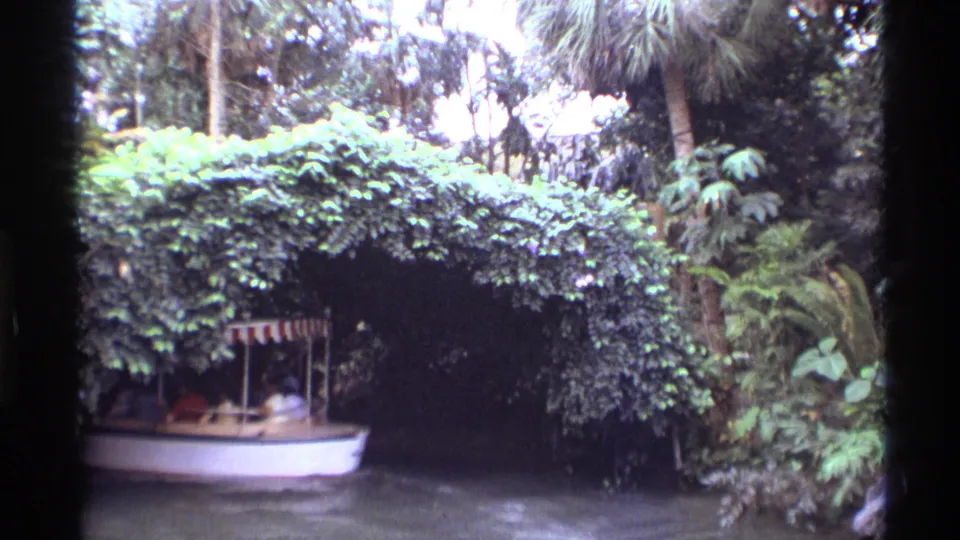 Home-movie view of a passenger boat passing a thick leafy arch during a 1974 Orlando ride.
