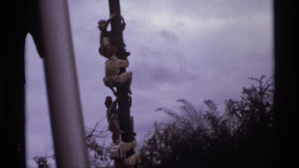 1974 Orlando 8mm frame showing a tilted, close visitor view of figures climbing or posed on a tall decorative pole.