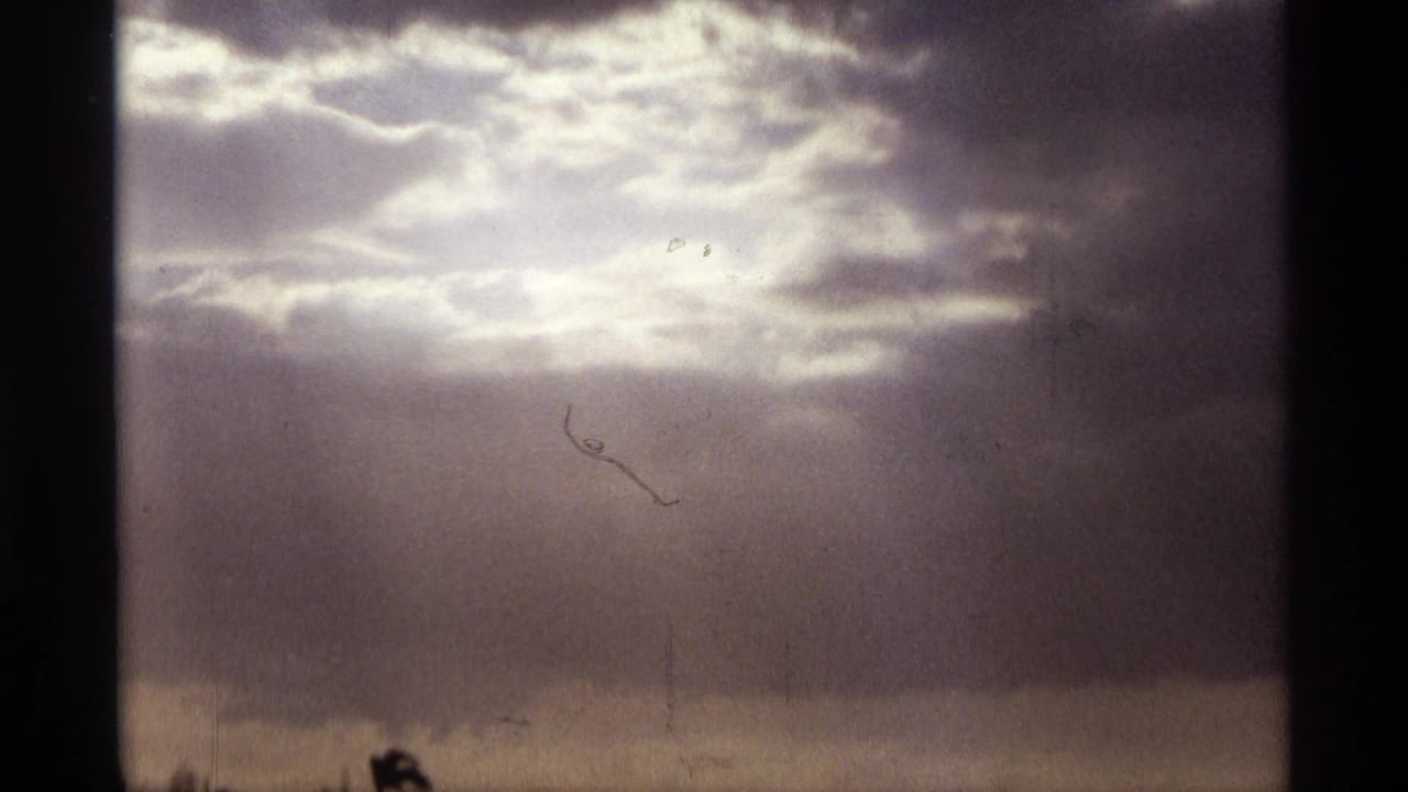 1974 Orlando 8mm frame showing bright sunlight diffused through layered clouds above a dark horizon line.