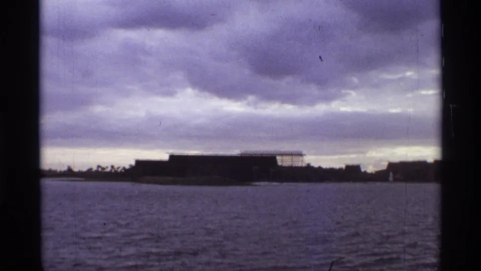 1974 Orlando 8mm frame looking across a waterway toward low buildings and a heavy overcast sky.