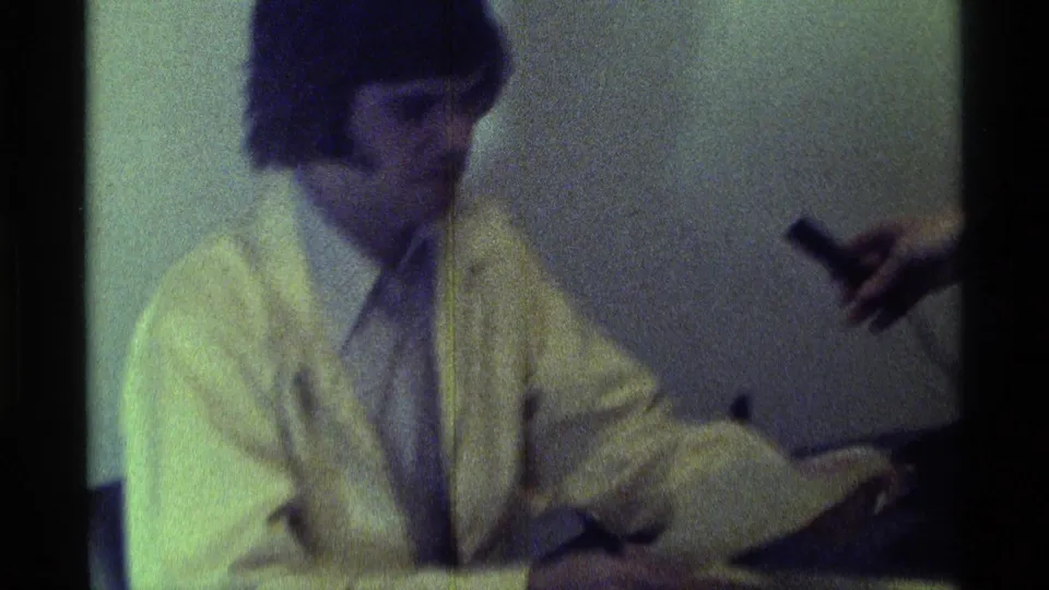 1976 Kentucky indoor home-movie frame showing the seated man turning during an informal microphone interview.