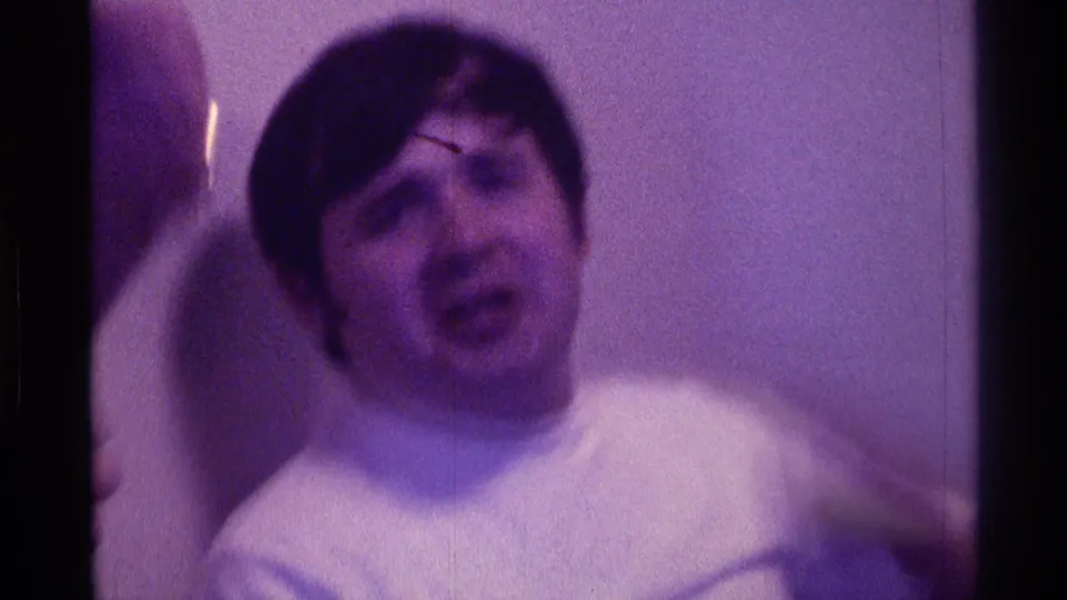 The 1976 Kentucky frame captures the young man indoors with his face lifted, mouth open, and hands raised in apparent surprise.