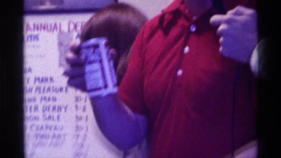 A person in a red shirt holds a canned drink beside a sign reading 2ND ANNUAL DERBY DAY in Kentucky home-movie footage.