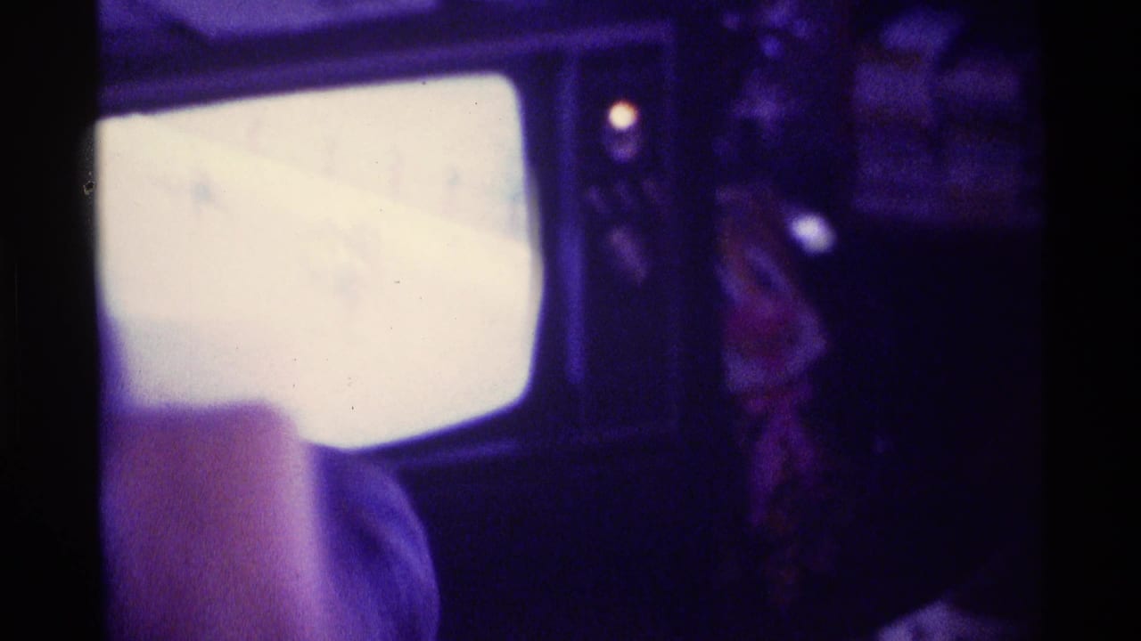 1976 Kentucky home-movie frame showing a glowing television in a dark living room with a person close to the set.