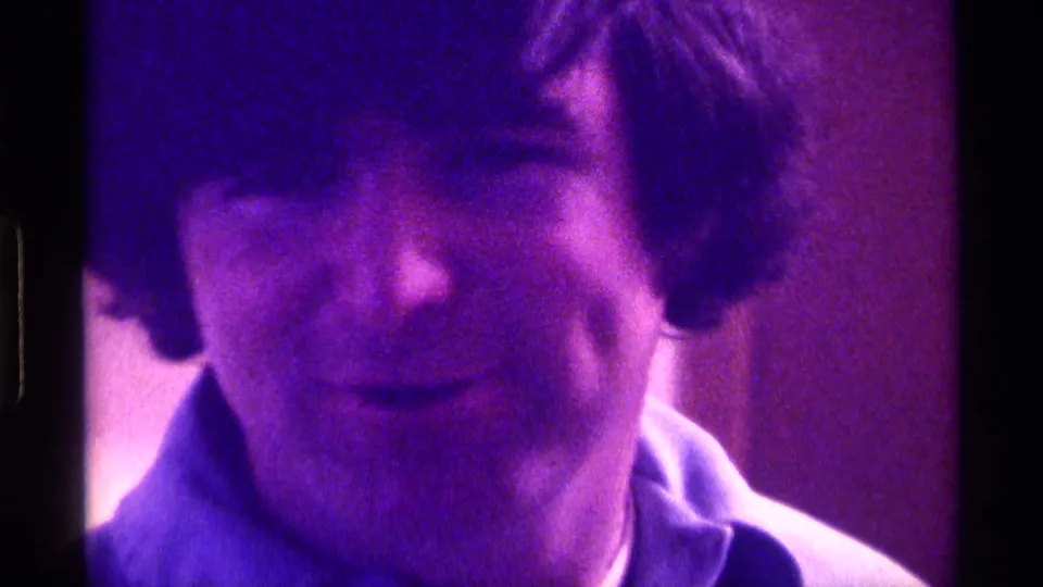 A soft, grainy 1976 Kentucky frame shows the young man looking downward as the purple-blue tint deepens.
