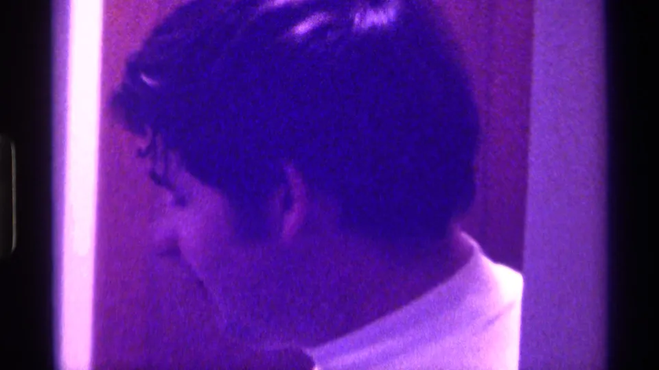 Profile view of the young man moving beside a bright vertical strip in a dim 1976 Kentucky interior.