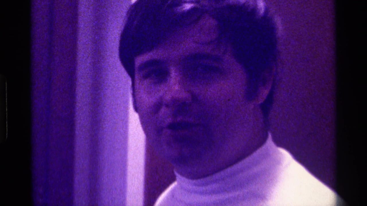 Close view of a man in a white turtleneck under purple lighting in 1976 Kentucky 8mm home-movie footage.