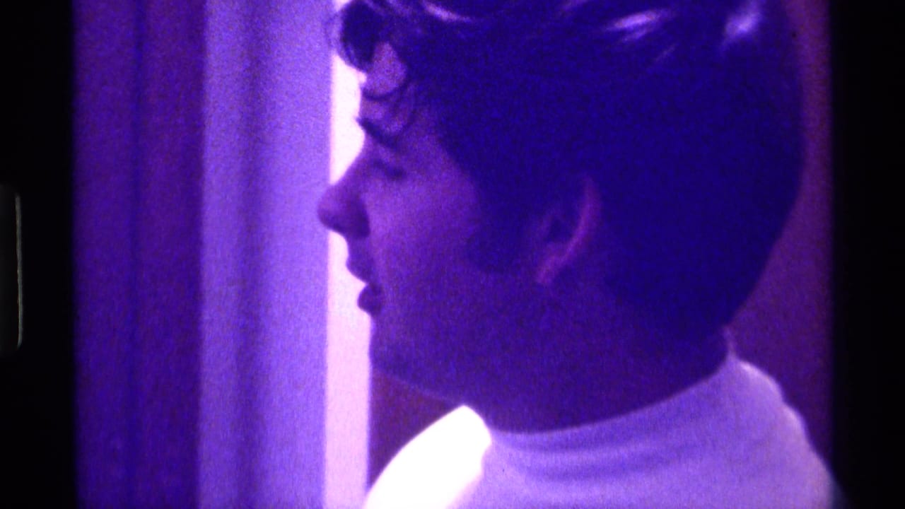 Young man in a white turtleneck seen in profile in 1976 Kentucky home-movie footage with a strong purple cast.