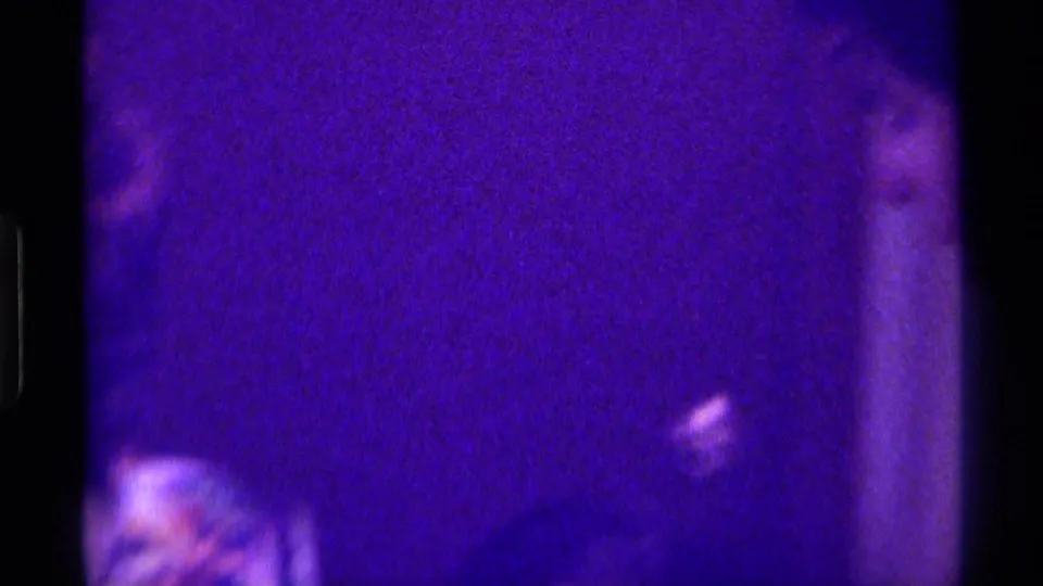 Dim, grainy 8mm frame from the Kentucky clip with a partially visible person at the right edge.