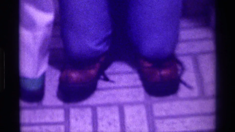 Upside-down frame shows the subject's jeans and brown shoes on tiled flooring, with strong purple color distortion.