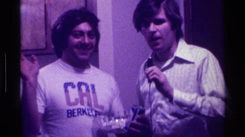 During the Kentucky home-movie party scene, one man raises his hand while the other appears to address the film taker with a microphone.
