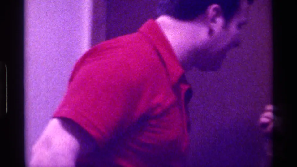 The final frame shows the man in the red shirt turned partly away, leaning or moving within the purple-tinted 8mm interior scene.