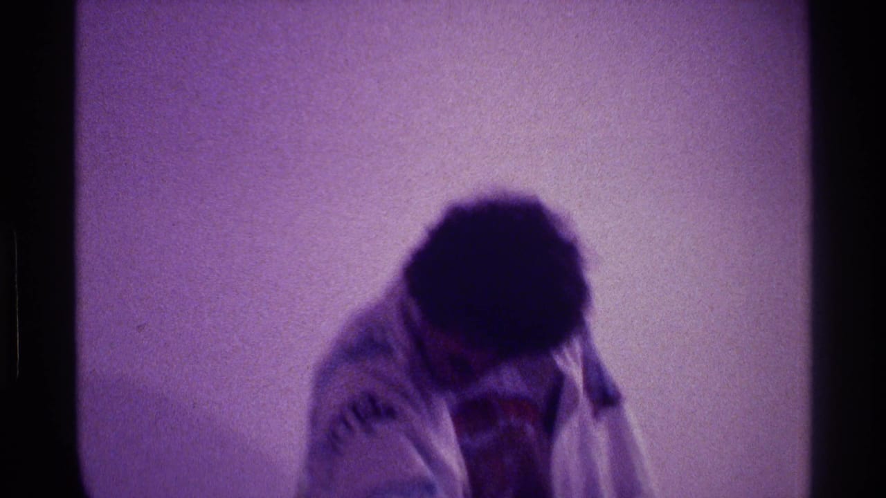 1976 Kentucky home-movie frame showing the dancer bending forward in a grainy indoor shot.