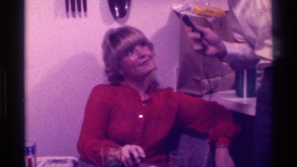 The woman sits in a Kentucky home interior as a microphone is held toward her, with utensils and a counter visible behind her.