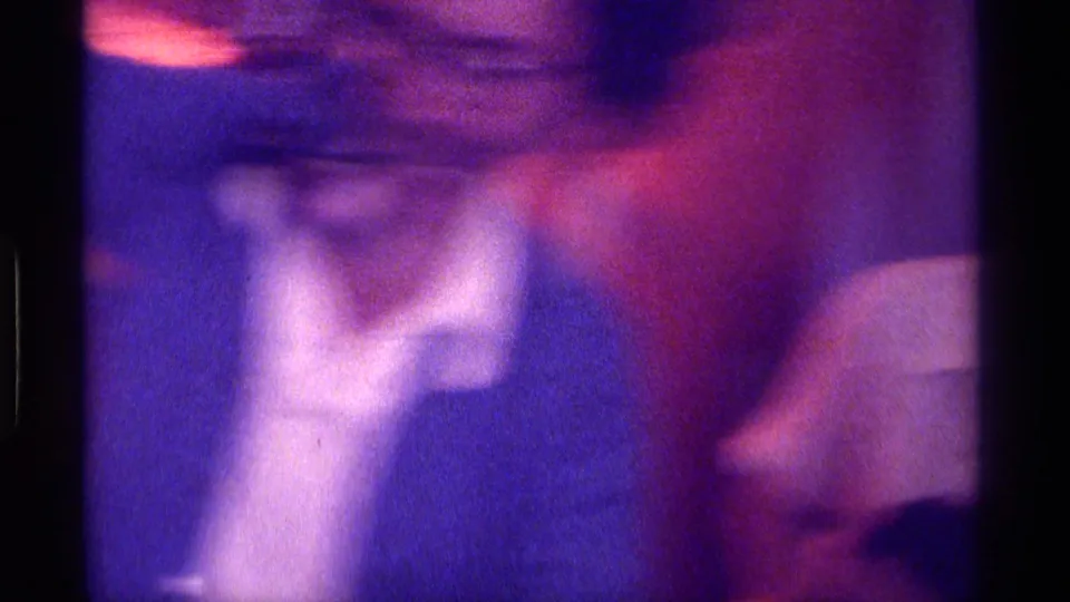 Soft, blurred Kentucky 1976 home-movie frame showing nearby people moving through an indoor gathering.