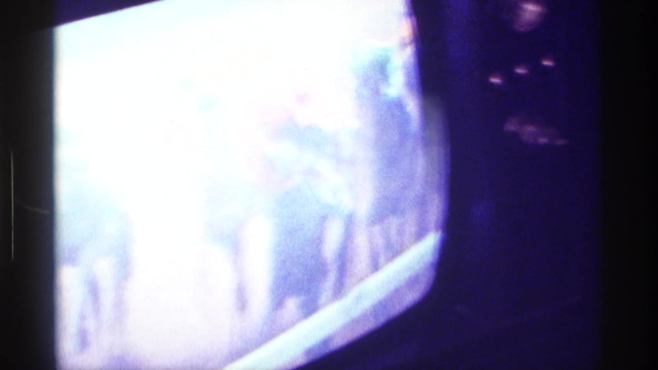 Blurred color television screen showing racing footage in a dark room.
