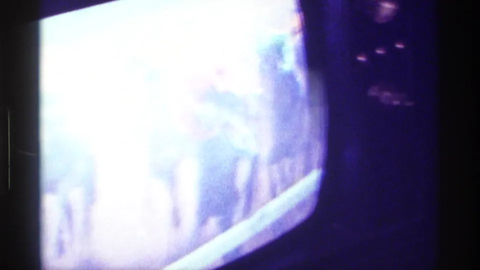 1976 Kentucky 8mm frame with a bright color television screen showing indistinct horse racing footage in a dim interior.