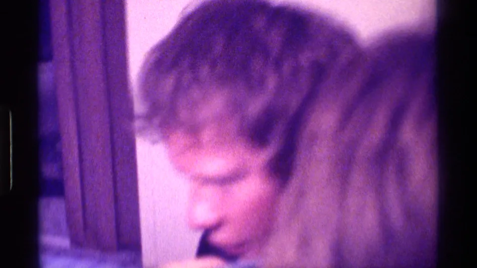 1976 Kentucky home-movie frame showing an adult viewer in profile beside wood trim during television viewing.