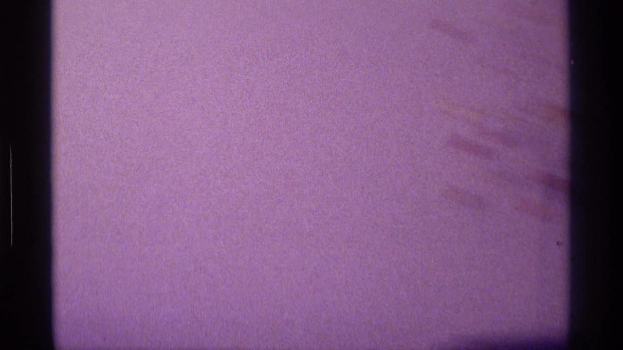 Purple-tinted film frame with a dark border and a blank or overexposed television area.