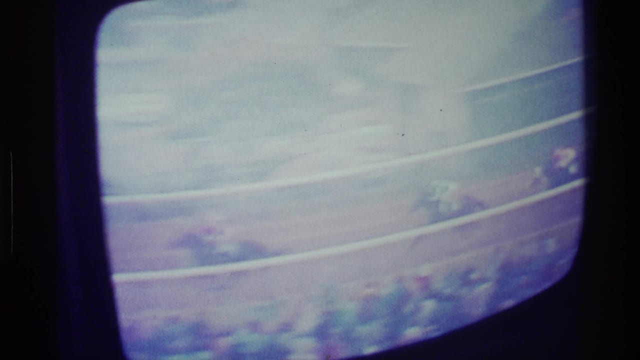 1976 Kentucky home-movie view of a rounded CRT screen showing horses and jockeys racing behind pale track rails.