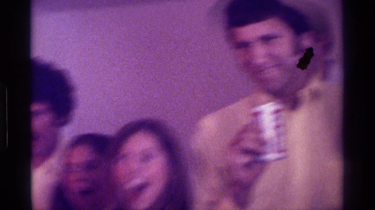 Adults at an indoor gathering, including a smiling man holding a beer can.